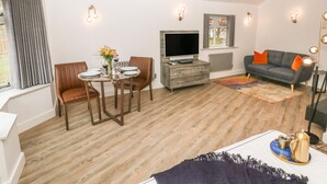 A modern living room with a dining area, a sofa, and a TV. - Hockerley Cottage (High Peak)