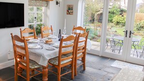 Un coin repas avec une table dressée pour quatre personnes, entourée de chaises en bois dotées d’assises rembourrées.