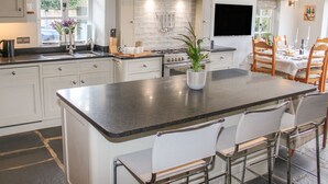 Une cuisine moderne dotée d’un îlot central, de tabourets de bar et d’un coin repas avec une table dressée pour six personnes.