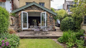 Une maison en pierre dotée d’un patio et de portes ouvertes donnant sur l’intérieur.