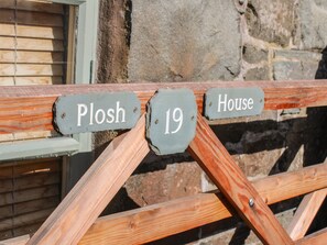 A wooden fence with house number signs reading "Plosh 19" and "House". - Plosh House (Keswick)