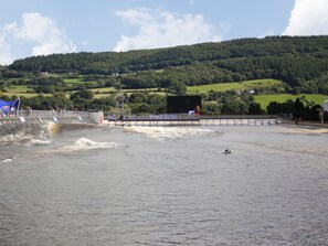 A waterfront area with a dam, a viewing platform, and a hillside in the background.