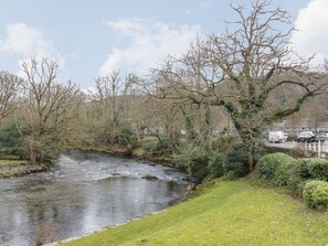 A river flowing through a park with trees and a bridge.