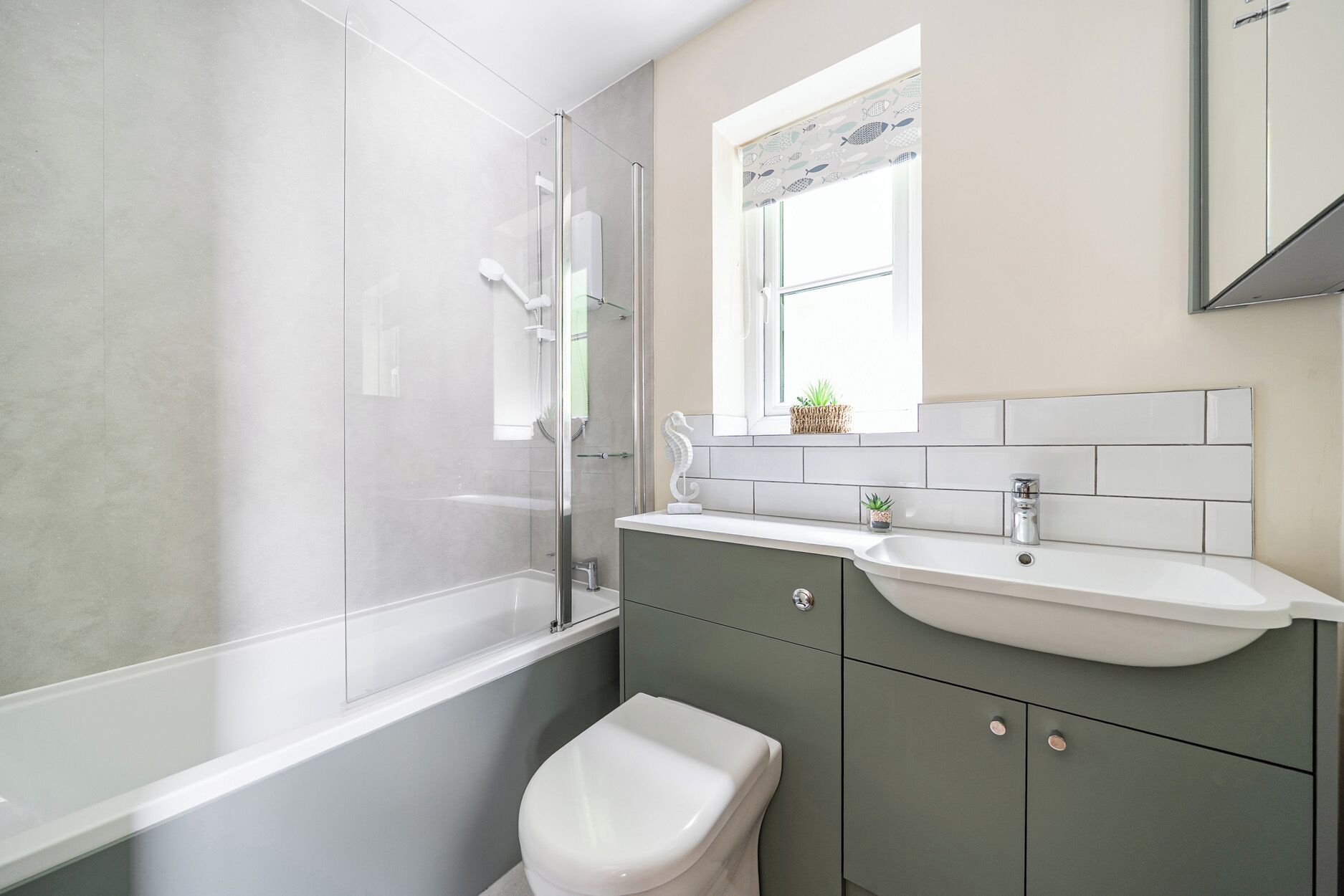 A bathroom with a glass shower enclosure, a white toilet, a sink with a mirror above, and a window with a view of the outside.