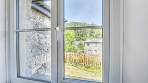 A window with a stone wall, a wooden fence, and a building in the background. - Tyn Y Ffynnon (Betws-Y-Coed)