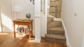 Un escalier avec un mur en pierre, une table en bois avec des livres et un globe terrestre.