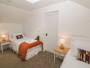 A bedroom with a bed, two bedside tables, a nightstand, a door, and a window. - Holly Cottage (Sheffield)