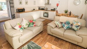 Un appartement moderne avec deux canapés beiges, une cuisine et un coin repas.