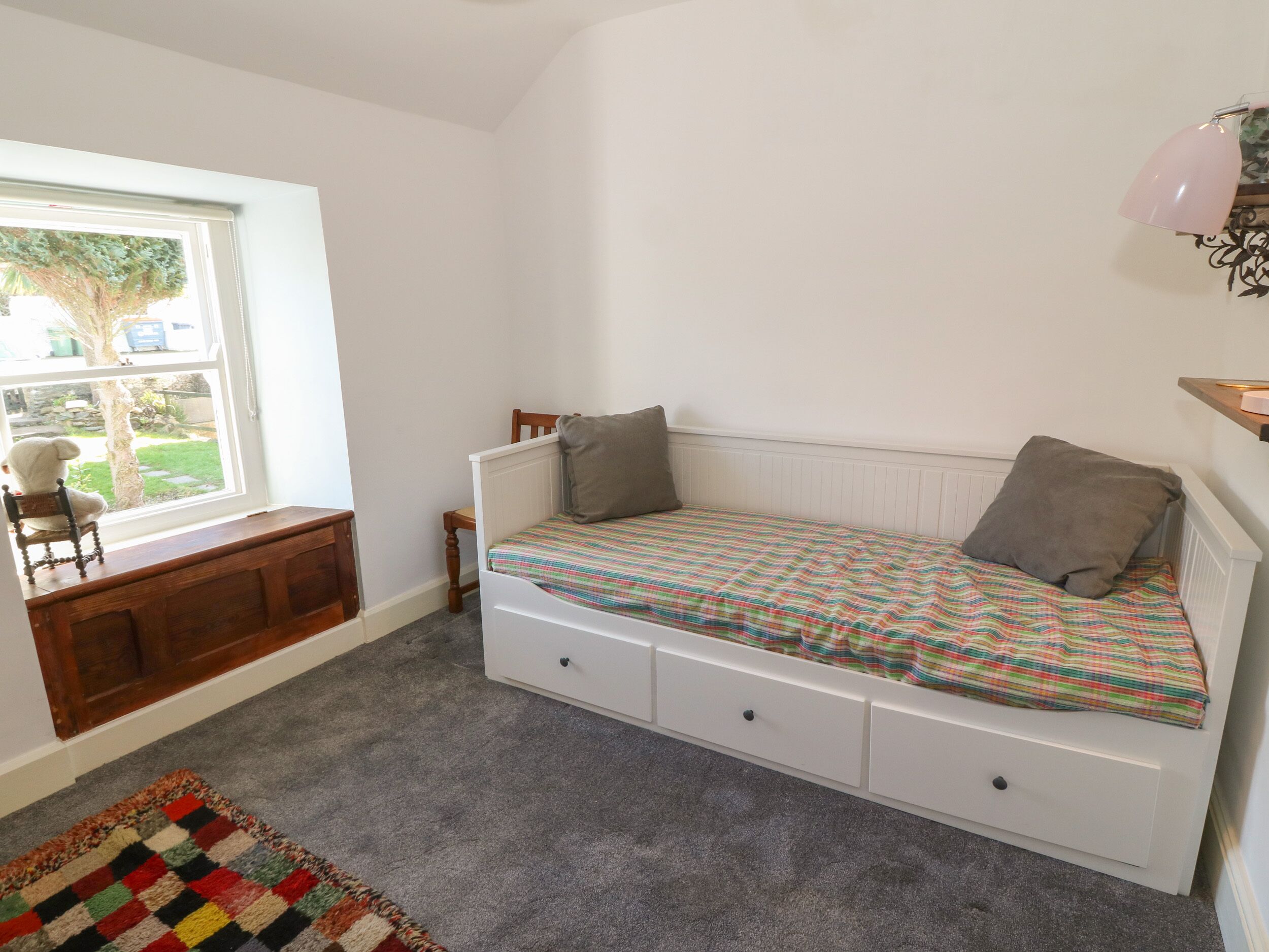 Un dormitorio con una cama individual, un escritorio pequeño, una silla y una ventana con vistas al exterior.