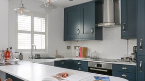 A modern kitchen with a central island, stainless steel appliances, and blue cabinetry. - 126 Main Street (Keighley)