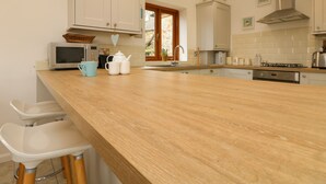Een moderne keuken met witte kastjes, een houten aanrechtblad, een magnetron, een waterkoker en een broodrooster.