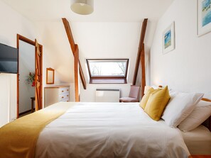 A bedroom with a large bed, a skylight, a chair, and a dresser. - Little Leighs (Launceston)
