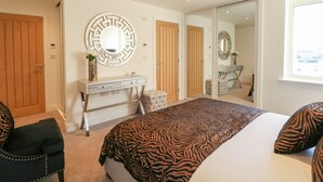 Une chambre avec un grand lit, une coiffeuse avec un miroir et un placard à portes coulissantes.