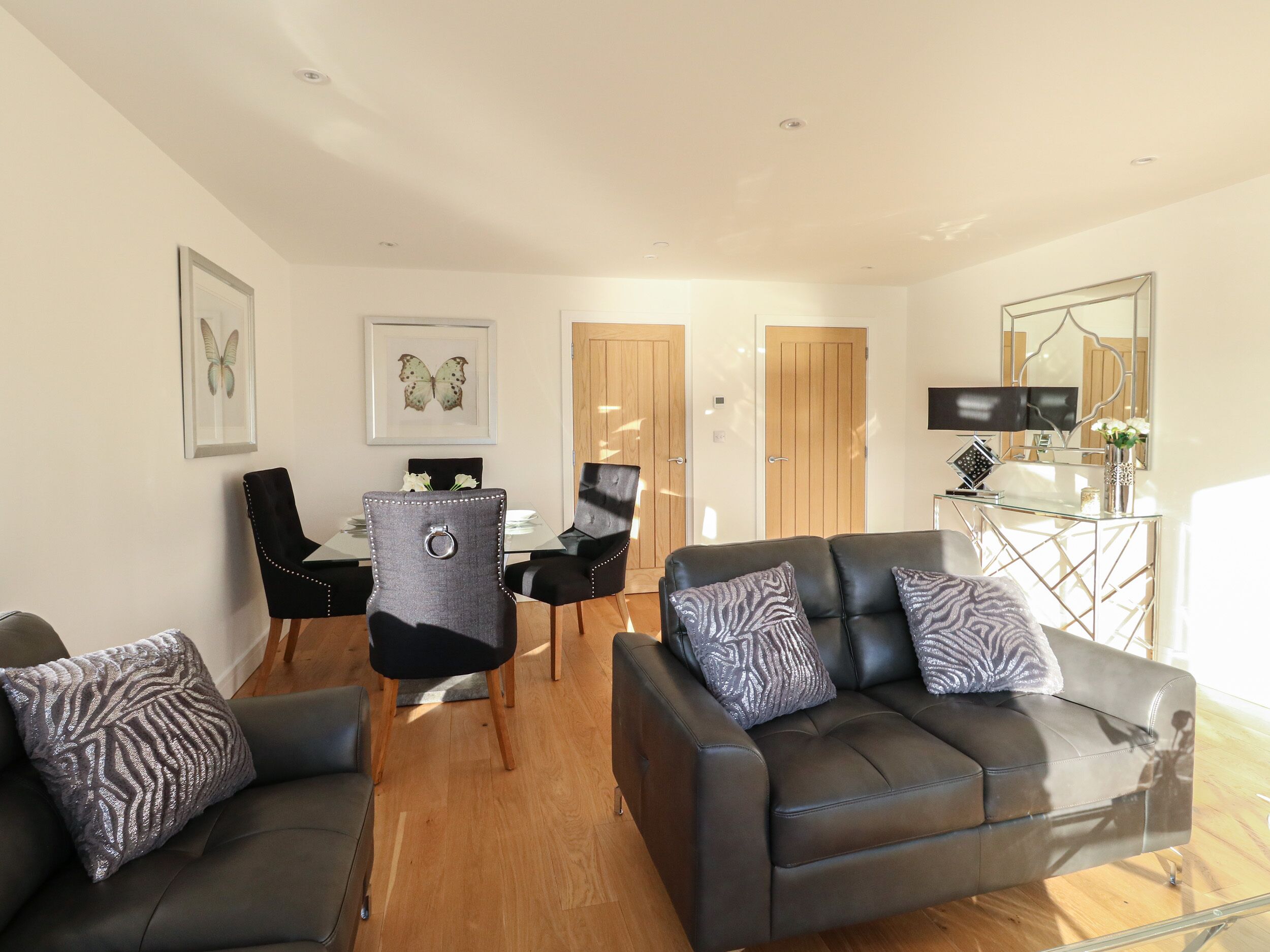 A modern living room with a sofa, two chairs, a dining table, and a TV.