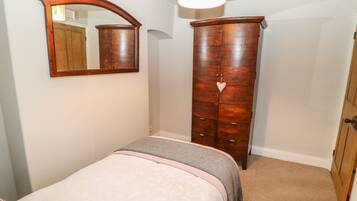 A bedroom with a bed, a wardrobe, and a mirror.