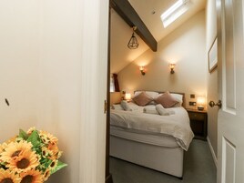 Un dormitorio con cama, mesitas de noche, lámpara y ventana.