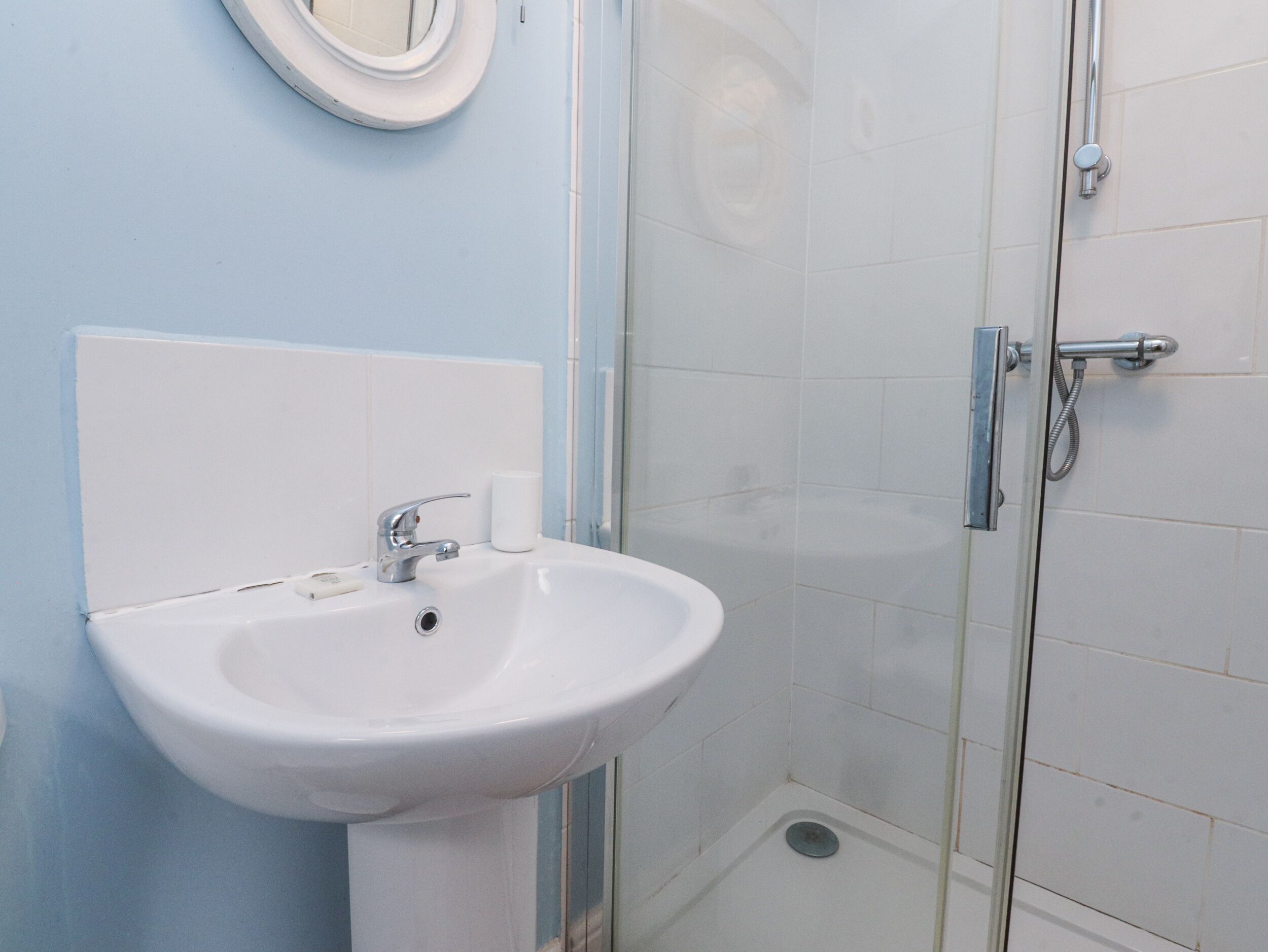 A bathroom with a white sink, a mirror, and a glass shower enclosure.