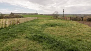A rural landscape with a wooden fence, open fields, and wind turbines in the distance. - Orchard Chalet (Liskeard)