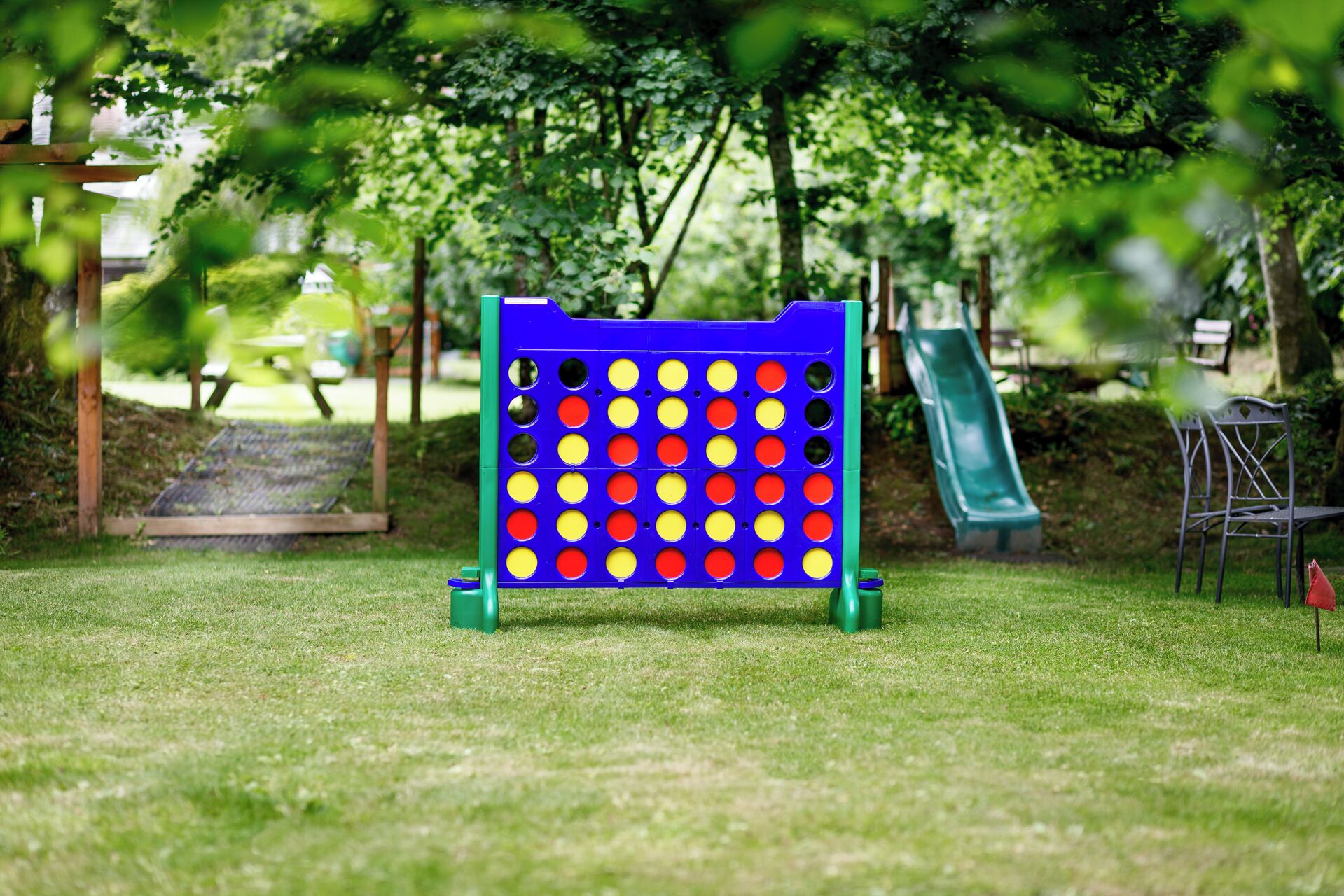 A board game setup in a park with a slide and benches in the background.