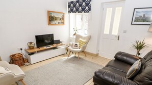 A living room with a TV, sofa, armchair, and a rug. - Daisy Cottage (Leyburn)