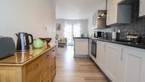 Une cuisine moderne avec des meubles en bois, un plan de travail et un coin repas comprenant une chaise et une table.