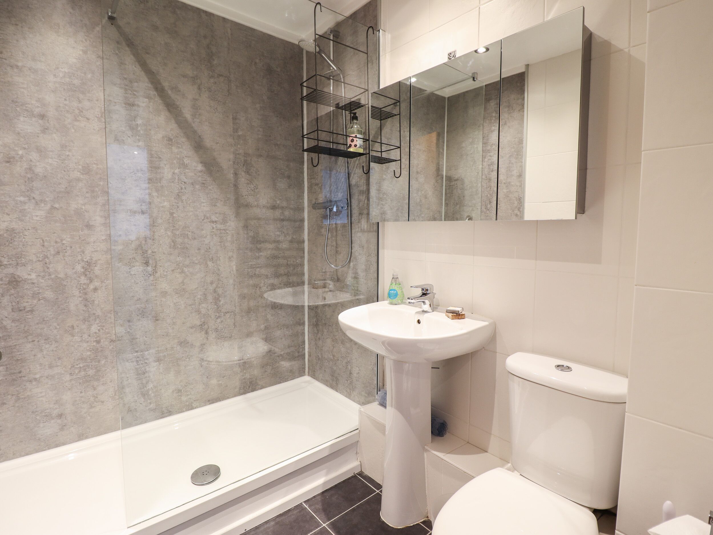 Un bagno moderno con cabina doccia in vetro, un lavandino bianco e un water.
