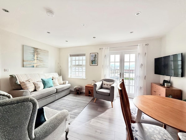A living room with a sofa, armchair, and a dining table.