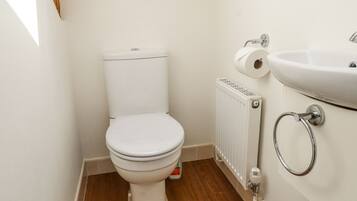 Un baño pequeño y limpio con un inodoro blanco, un lavabo blanco y un radiador.