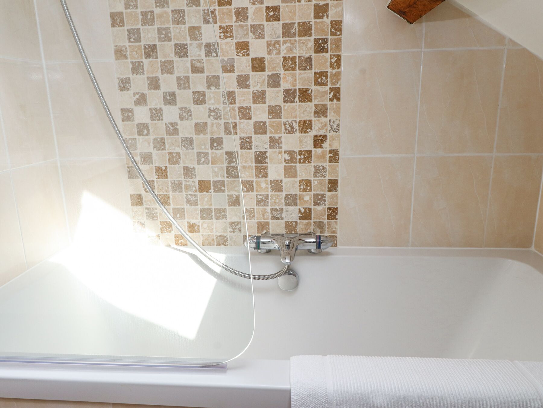 Un baño con bañera, ducha y pared con azulejos.