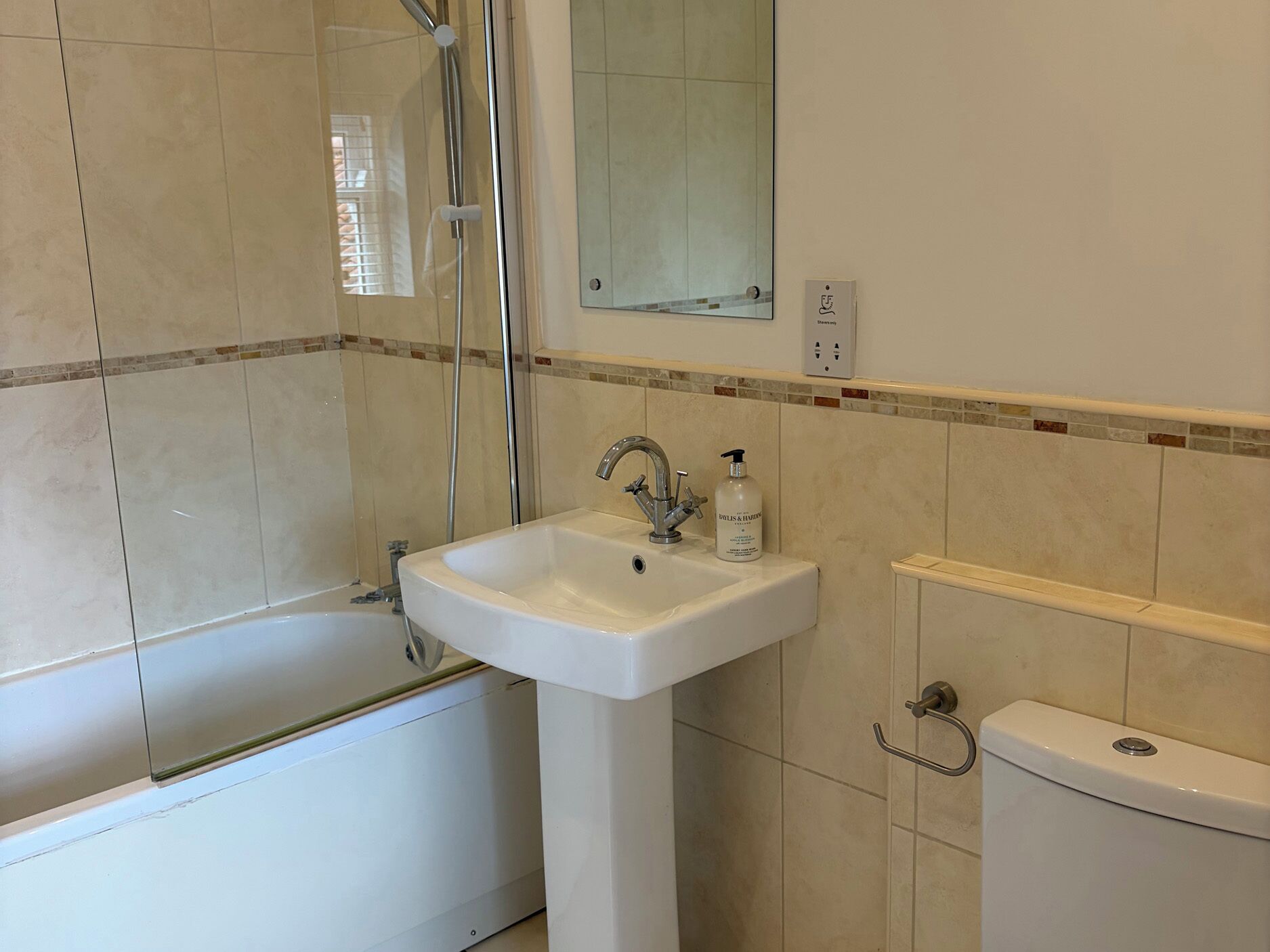 A bathroom with a bathtub, a sink, a toilet, and a mirror.