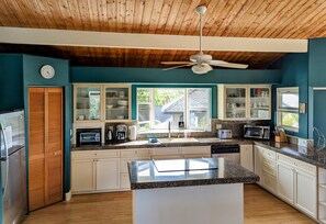 Enjoy cooking in this well-equipped kitchen with a large island, stainless steel appliances, and a window offering a view of the outside.
