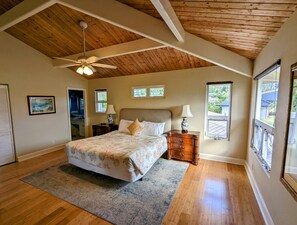 Cozy retreat with a large bed, nightstand, and dresser, offering a peaceful view of the outdoors.