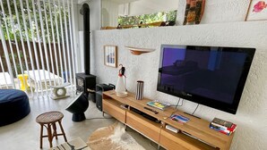 Ein modernes Wohnzimmer mit großem Flachbildfernseher, einer Holzunterhaltungsecke und einer gemütlichen Sitzecke mit Teppich.