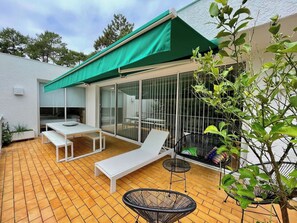 A patio with a table, two lounge chairs, a small round table, and a green awning. - Interesting architect villa very close to beach A0032 (Lège-Cap-Ferret)