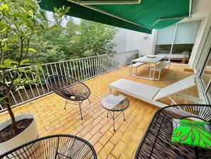 A balcony with a wooden floor, white lounge chairs, a small table, and a green umbrella. - Interesting architect villa very close to beach A0032 (Lège-Cap-Ferret)