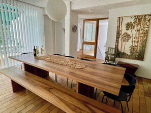 Een moderne eetruimte met een lange houten tafel, banken en zwarte stoelen.