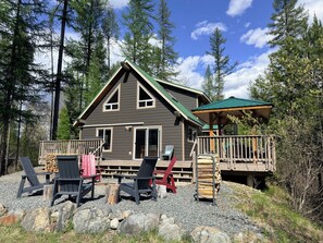 A cabin with a deck, outdoor seating, and a covered area. - Moyie Lake Cabin (Moyie)