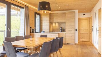 A modern kitchen with wooden cabinets, a central island, and a dining area with a wooden table and chairs.