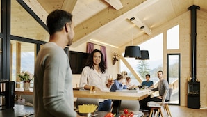 A modern kitchen with a central island, wooden beams, and a large window overlooking a mountainous landscape. - Superior Chalet with 5 bedrooms, sauna & pool (Haus im Ennstal)