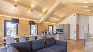 A modern interior with a wooden ceiling, a sofa, dining area, and kitchen.