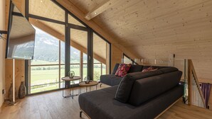 A modern interior with a large window, a sofa, and a small table. - Premium Apartment gallery with 3 bedrooms and sauna & whirlpool (Haus im Ennstal)