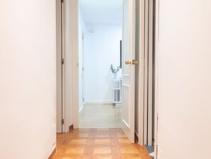 A hallway with a tiled floor, white walls, and a door with a golden handle.