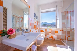 A modern bathroom with a large sink, mirror, and shower.