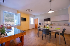 Une cuisine moderne avec un coin repas, un plancher en bois et une vue sur l’extérieur.