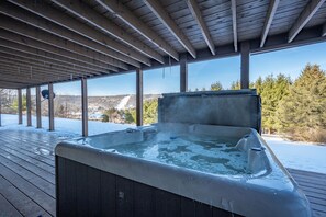 A hot tub under a wooden pergola with a snowy landscape in the background. - Dog Friendly Lakeview Cabin w/ Hot Tub (McHenry)