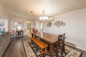 A dining area with a wooden table, benches, and a chandelier.