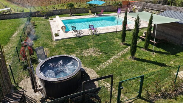 A swimming pool with lounge chairs, a hot tub, and a fenced garden area. - Charming Village House with Shared Heated Pool, Near Attractions, and Private Garden (Le Menoux)