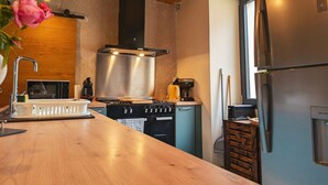 A kitchen with a wooden ceiling, stainless steel appliances, and a wooden countertop. - Charming Village House with Shared Heated Pool, Near Attractions, and Private Garden (Le Menoux)