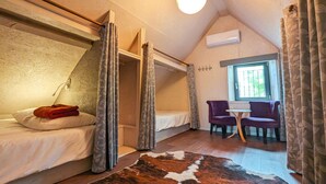 A bedroom with a bunk bed, a desk, two chairs, a cowhide rug, and a window with curtains. - Charming Village House with Shared Heated Pool, Near Attractions, and Private Garden (Le Menoux)