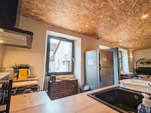 A compact kitchen with a window, a refrigerator, a sink, and a stove. - Charming Village House with Shared Heated Pool, Near Attractions, and Private Garden (Le Menoux)